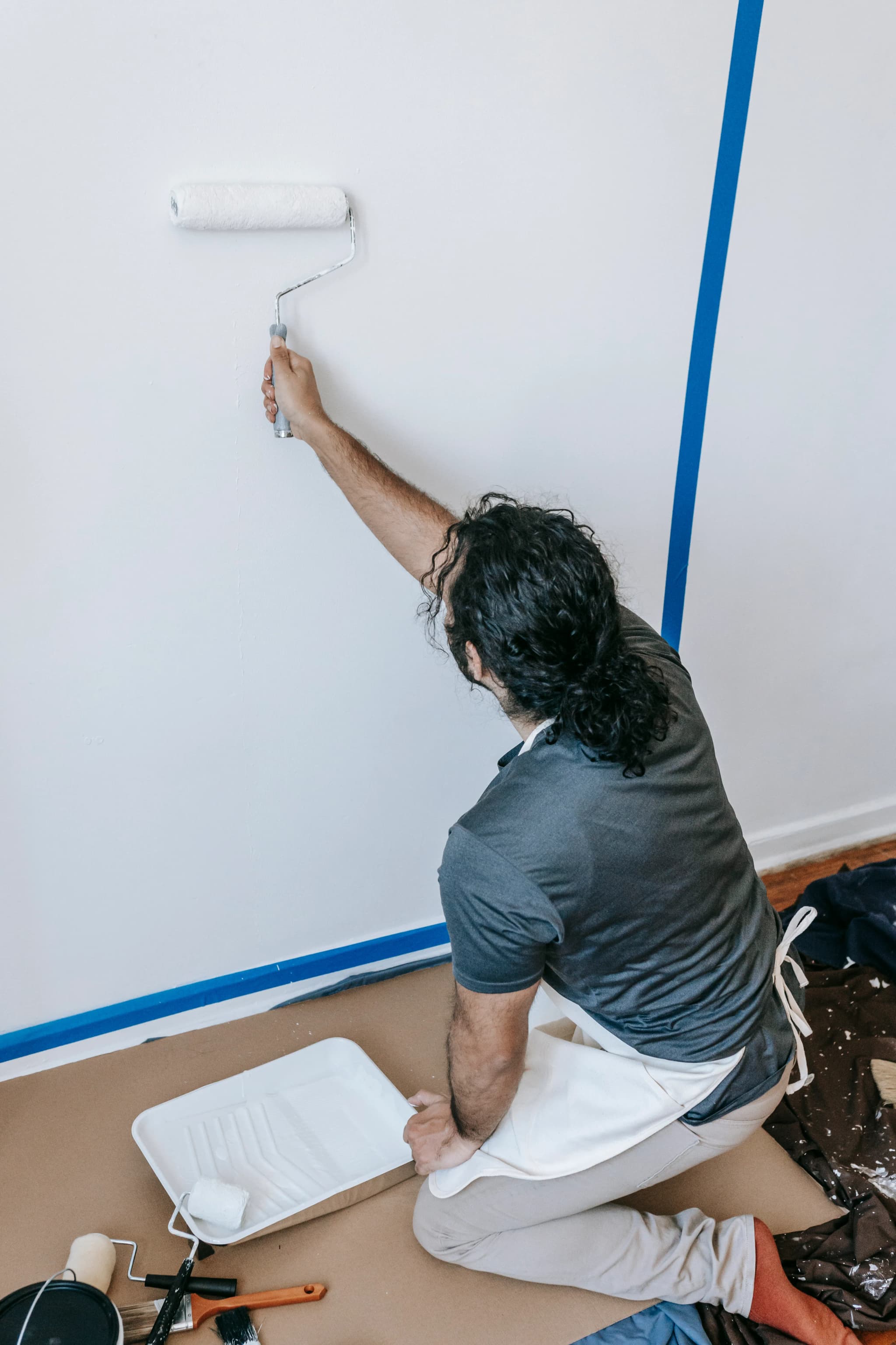 Painter rolling a fresh coat onto a taped wall